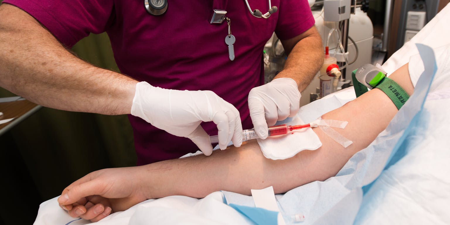 Een verpleegster die een injectie geeft aan een patiënt in een ziekenhuisbed.