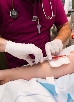 Een verpleegster die een injectie geeft aan een patiënt in een ziekenhuisbed.