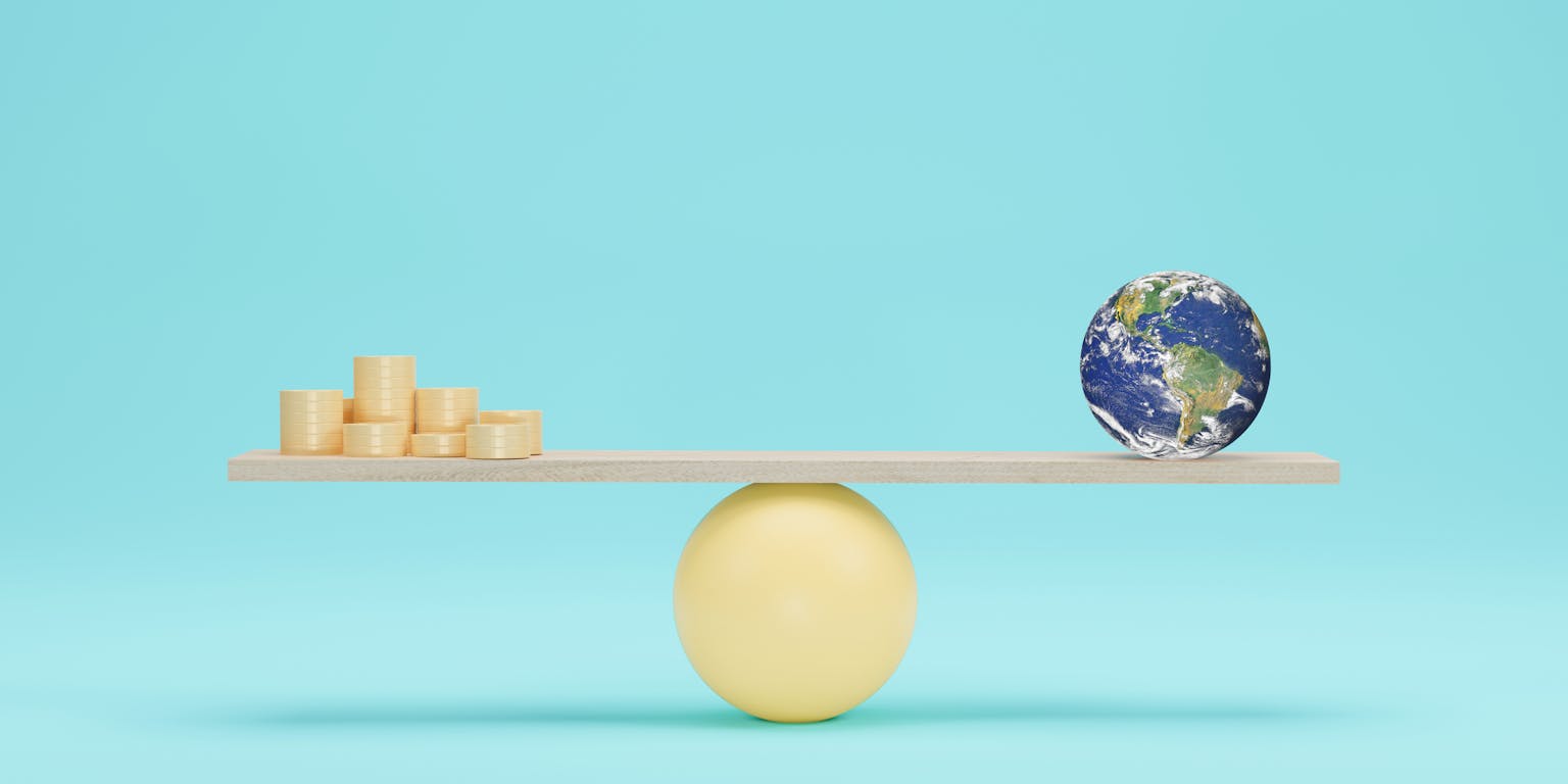 een balans met aan de ene kant een mini-aarde en aan de andere kant geld, die elkaar in evenwicht houden