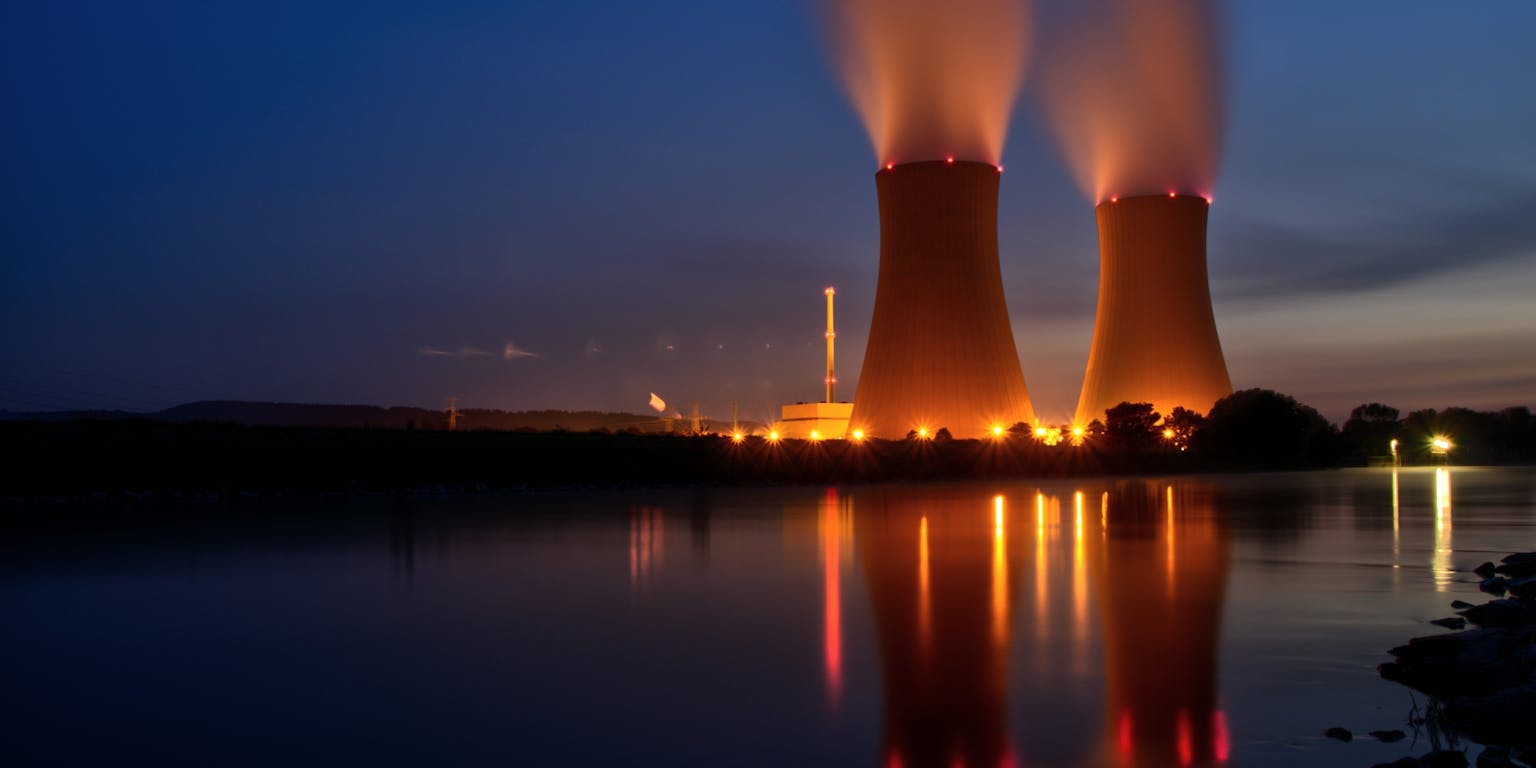 Twee verlichte kerncentrales in de avond.
