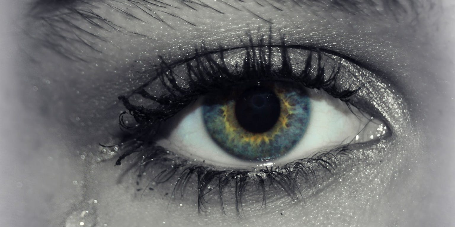 Een close-up van het oog van een vrouw met tranen erop.