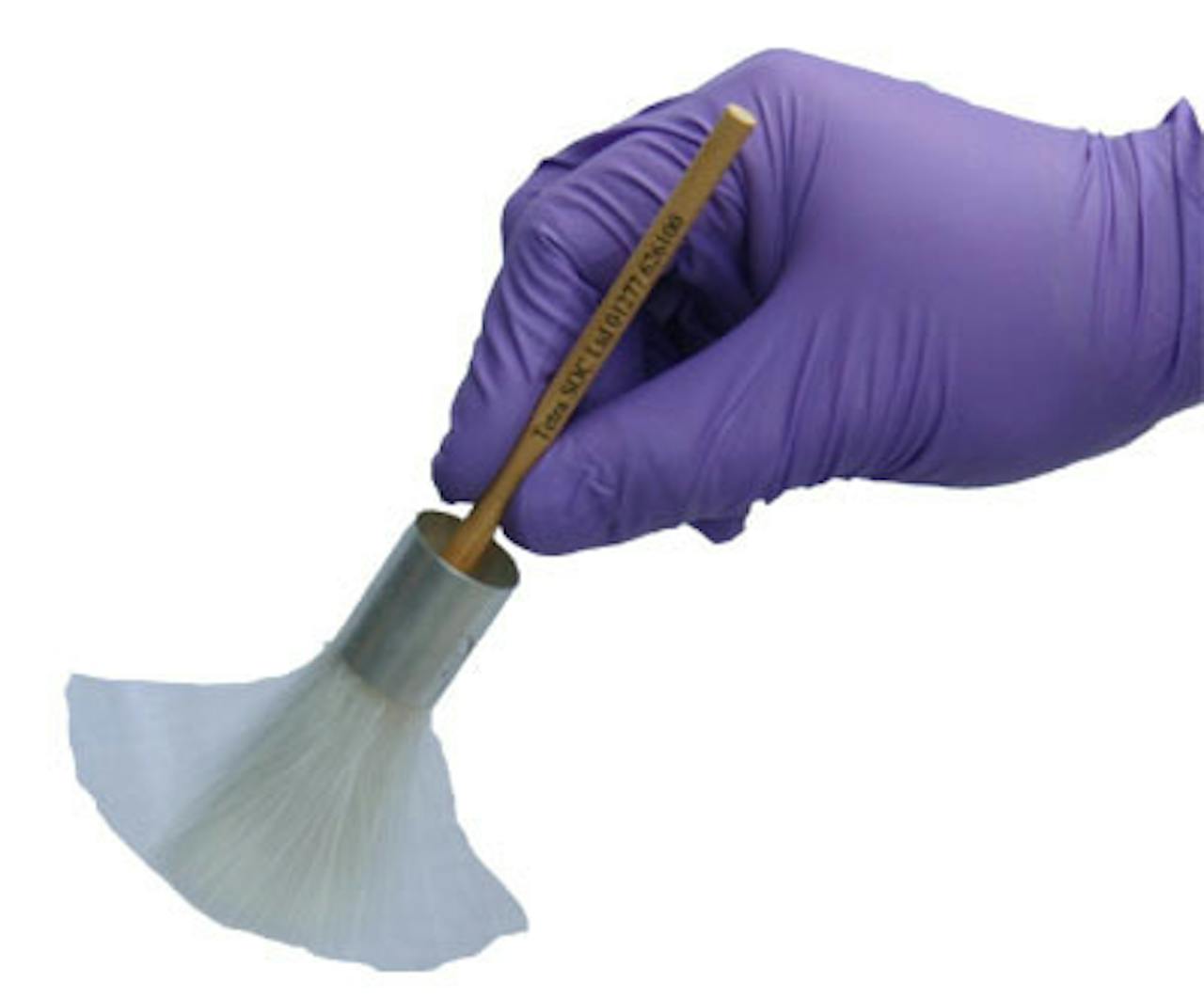 Een hand die een witte borstel vasthoudt in paarse handschoenen.