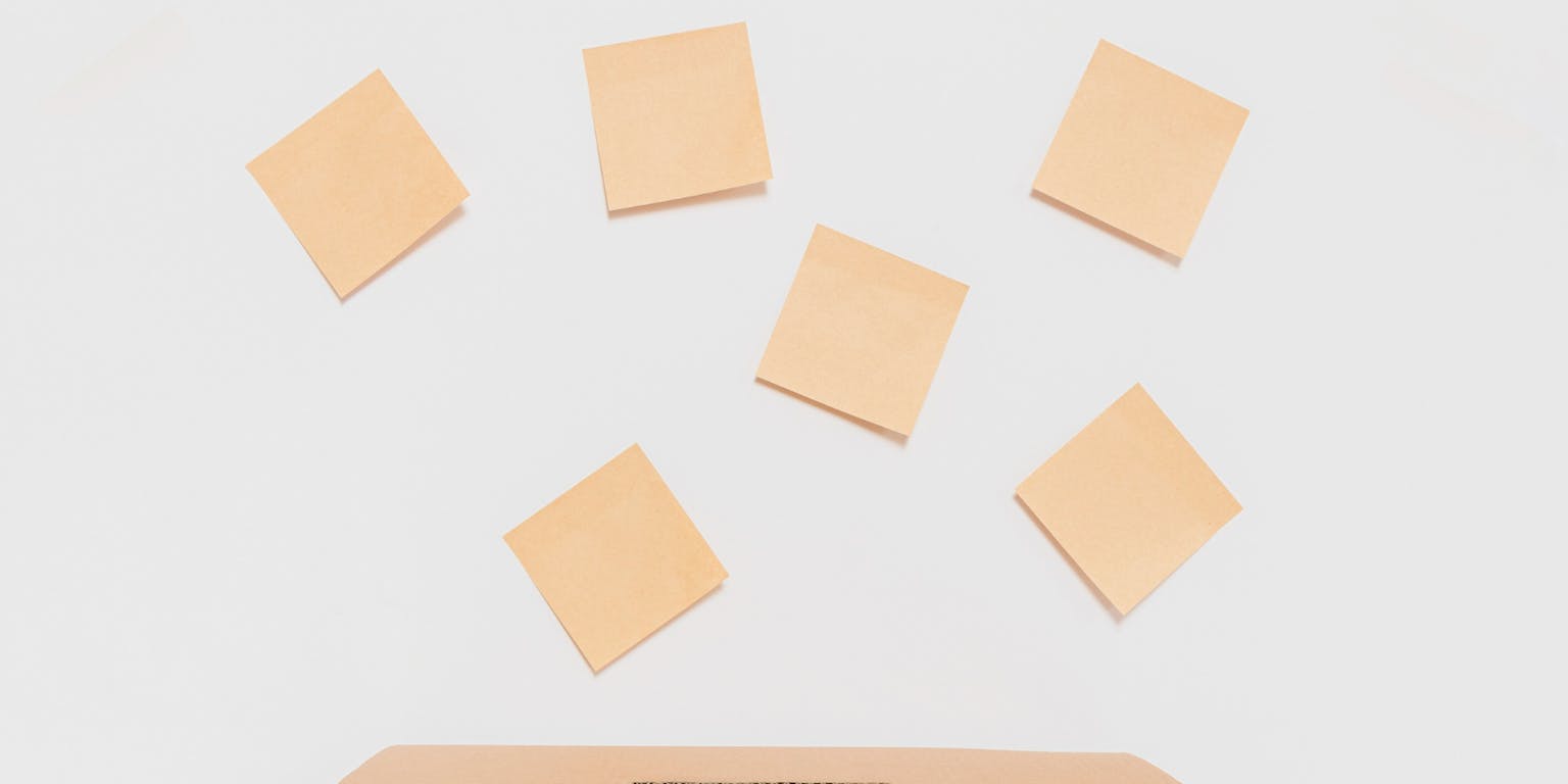 Een bruine doos met een gleuf erin. Erboven zweven briefjes in dezelfde kleur.