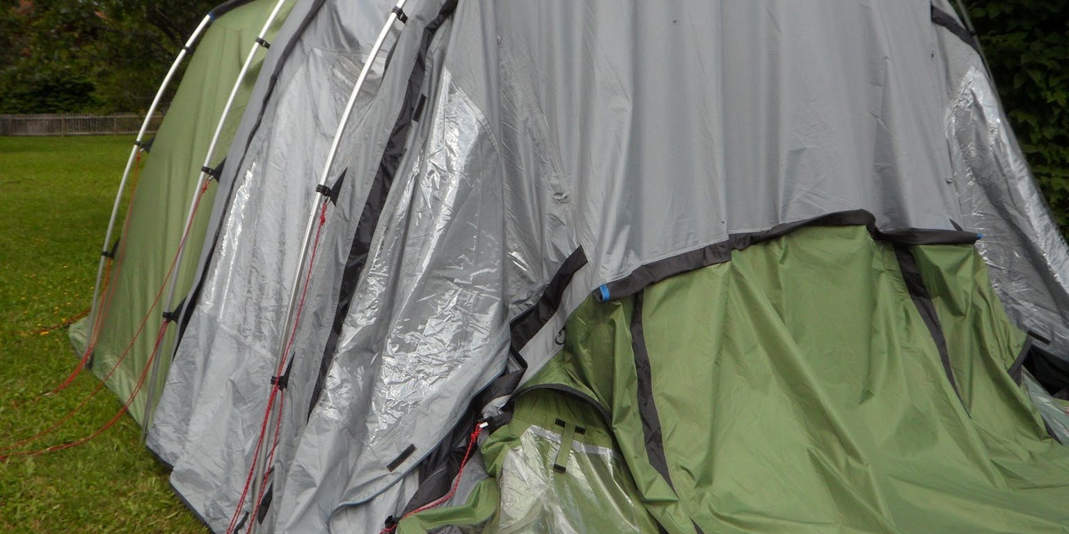 Een groen-grijze tent op een grasveld.