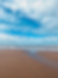 Een zandstrand met een blauwe lucht en wolken.
