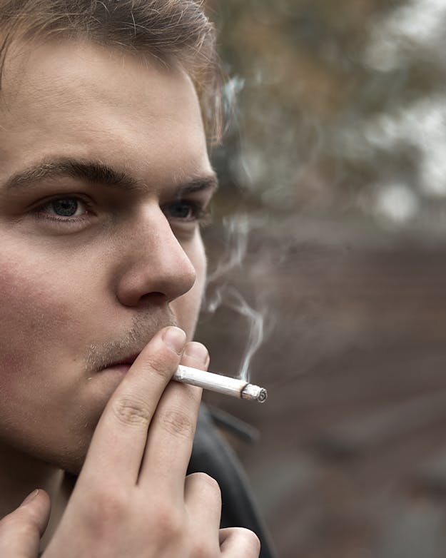 Jonge man rookt een sigaret Jonge man rookt een sigaret