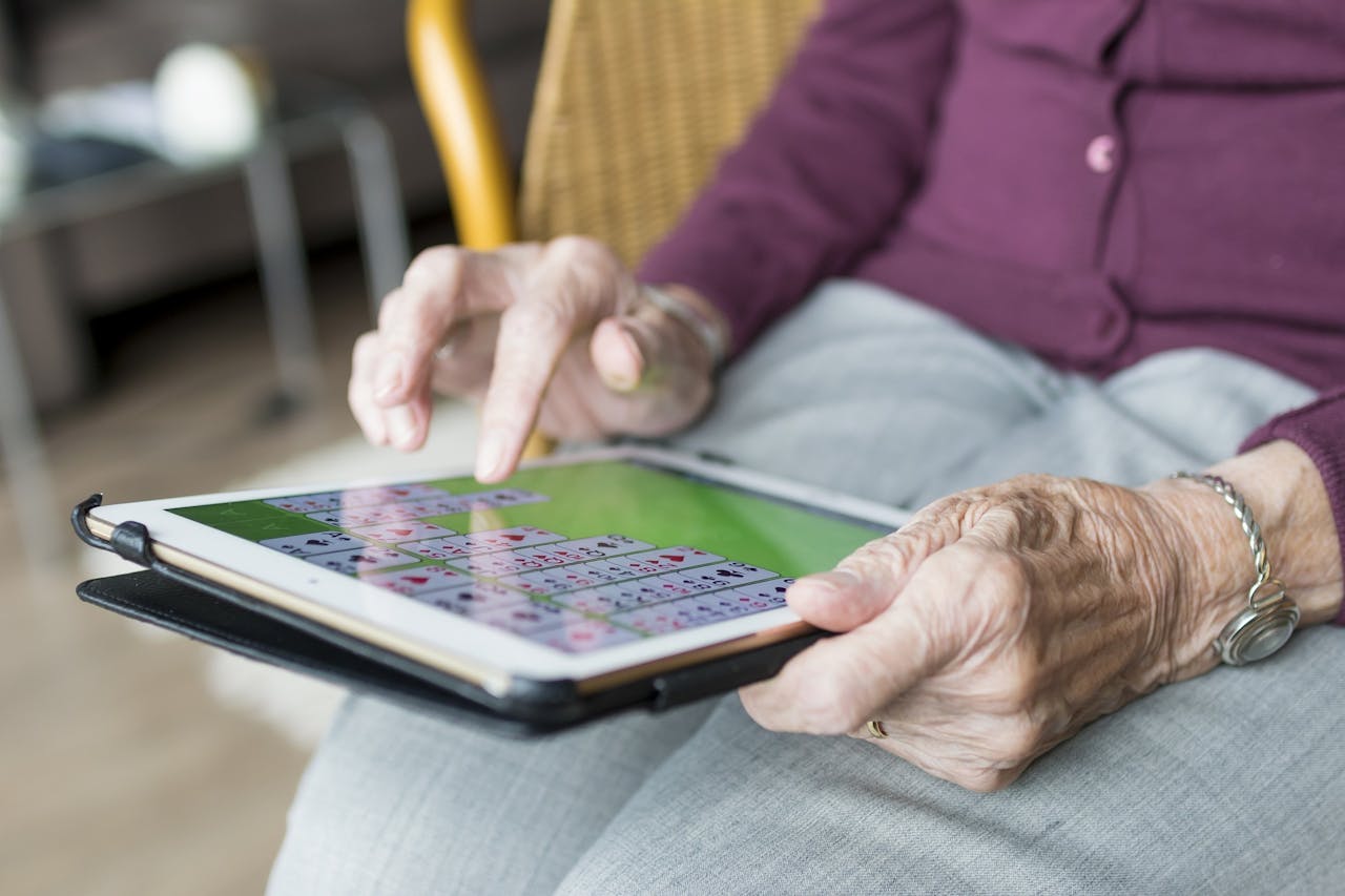 Een oudere vrouw die een kaartspel speelt op een tablet.
