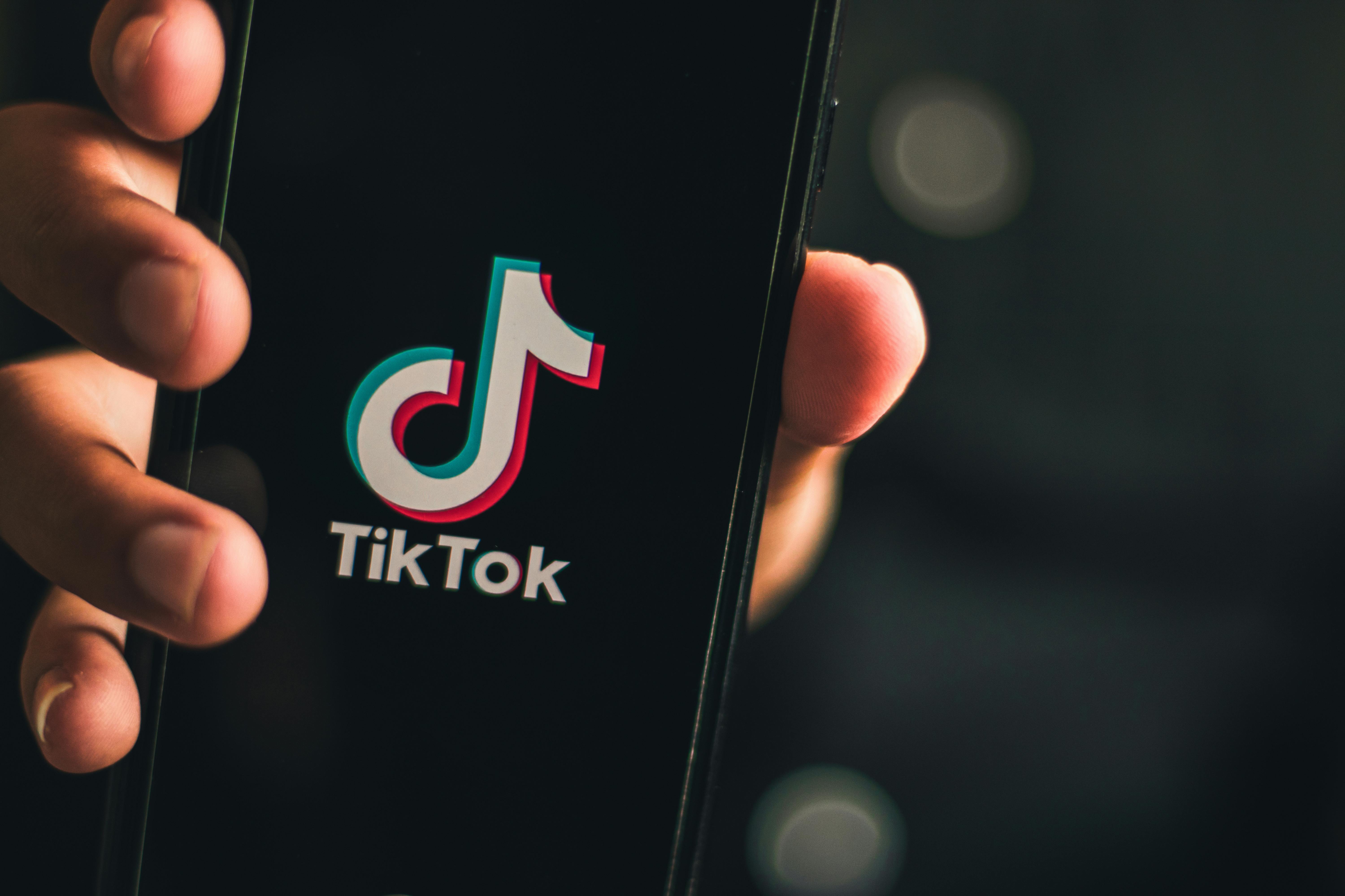 Een hand houdt een smartphone vast. Op het scherm is het logo van TikTok te zien.