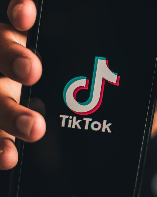 Een hand houdt een smartphone vast. Op het scherm is het logo van TikTok te zien. Een hand houdt een smartphone vast. Op het scherm is het logo van TikTok te zien.