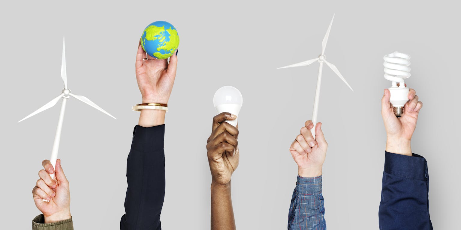 handen houden onderdelen vast van de energietransitie; windmolens, de aarde, lampen
