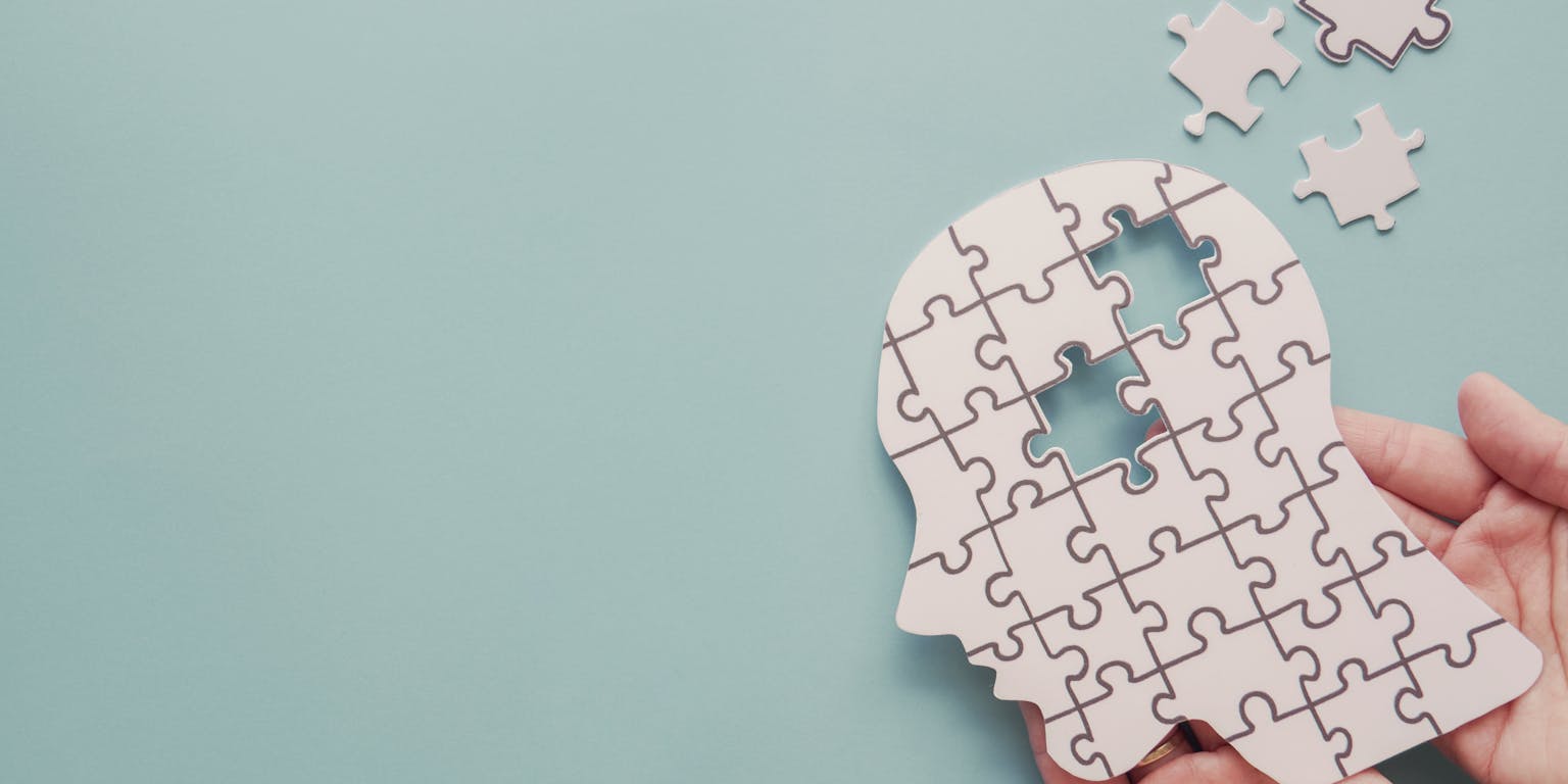 puzzel van menselijk hoofd waarbij een aantal puzzelstukjes uit het hoofd zijn gevallen