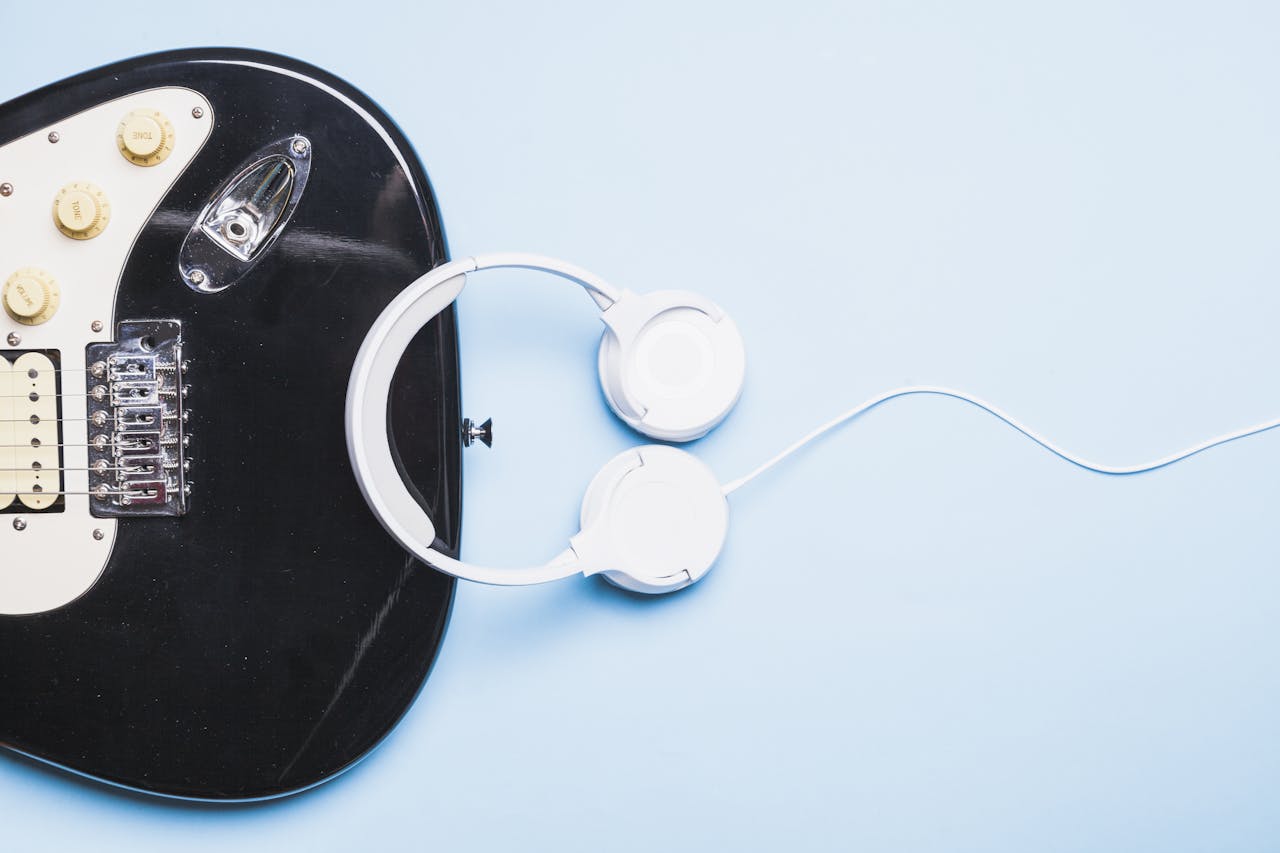 Muziek kun je beschrijven met genres zoals pop en rock. gitaar en witte koptelefoon