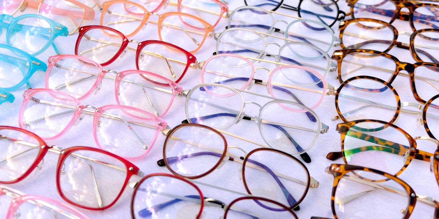 Een tafel vol verschillende brilmonturen in uiteenlopende kleuren.