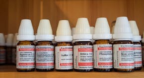 Een plank met een rij flesjes, gevuld met verschillende homeopatische middelen.