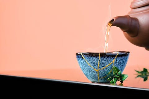 Kintsugi is een soort gouden lijm die benadrukt (in plaats van verhult) dat een kopje in het verleden gebroken is. theekopje met kintsugi, een soort gouden lijm die benadrukt dat een kopje in het verleden gebroken is