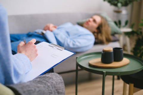Ook binnen de psychotherapie wordt steeds vaker hypnose toegepast om lang vergeten trauma's te verwerken. Man ligt op de sofa bij de therapeut