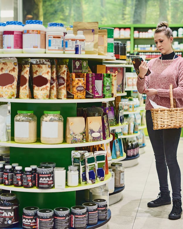 Vrouw met rieten winkelmandje in een winkel met voedingssupplementen Vrouw met rieten winkelmandje in een winkel met voedingssupplementen