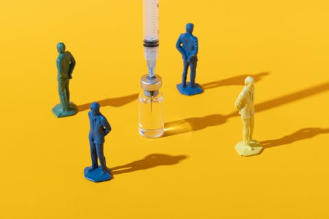 Ga in gesprek over waarom mensen geloven wat ze geloven, adviseert Van Tongeren. Vier plastic poppetjes staan met hun rug naar een injectienaald voor een vaccinatie