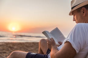 Een man die een boek leest op het strand.