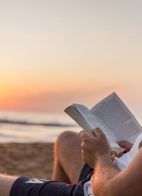 Een man die een boek leest op het strand.