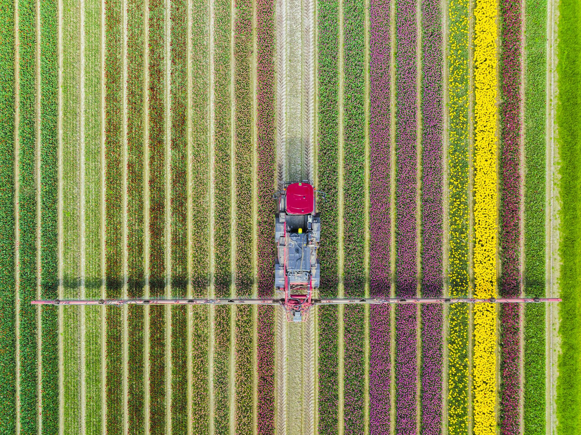 Een luchtfoto van een boer die zijn land met een traktor bewerkt.