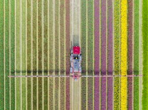 Een luchtfoto van een boer die zijn land met een traktor bewerkt.