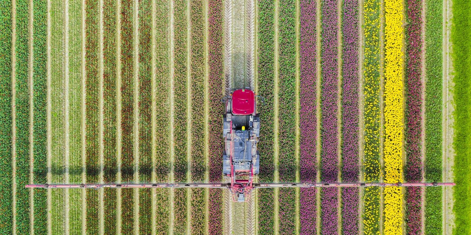 Een luchtfoto van een boer die zijn land met een traktor bewerkt.