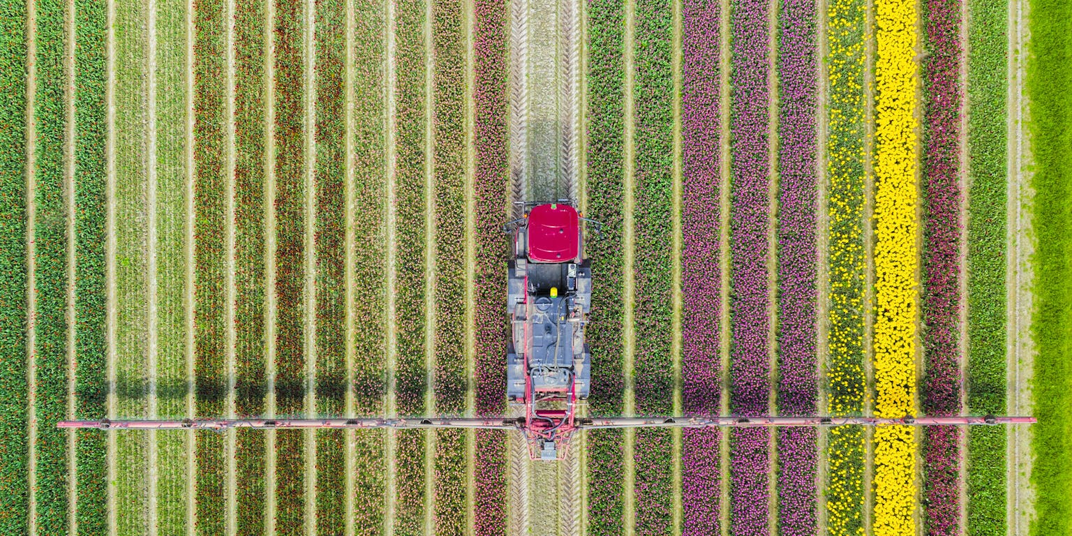 Een luchtfoto van een boer die zijn land met een traktor bewerkt.