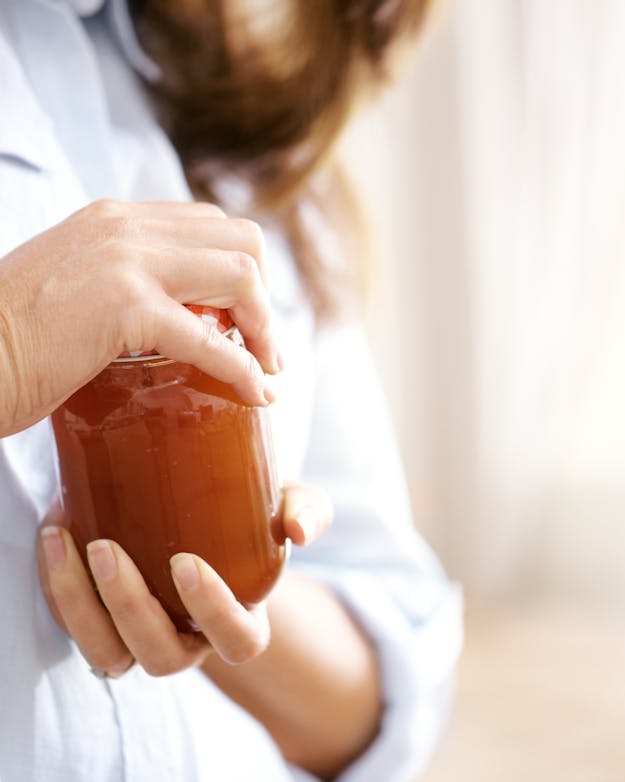 Vrouw heeft zichtbaar moeiten om een jampot open te draaien. Vrouw heeft zichtbaar moeiten om een jampot open te draaien.