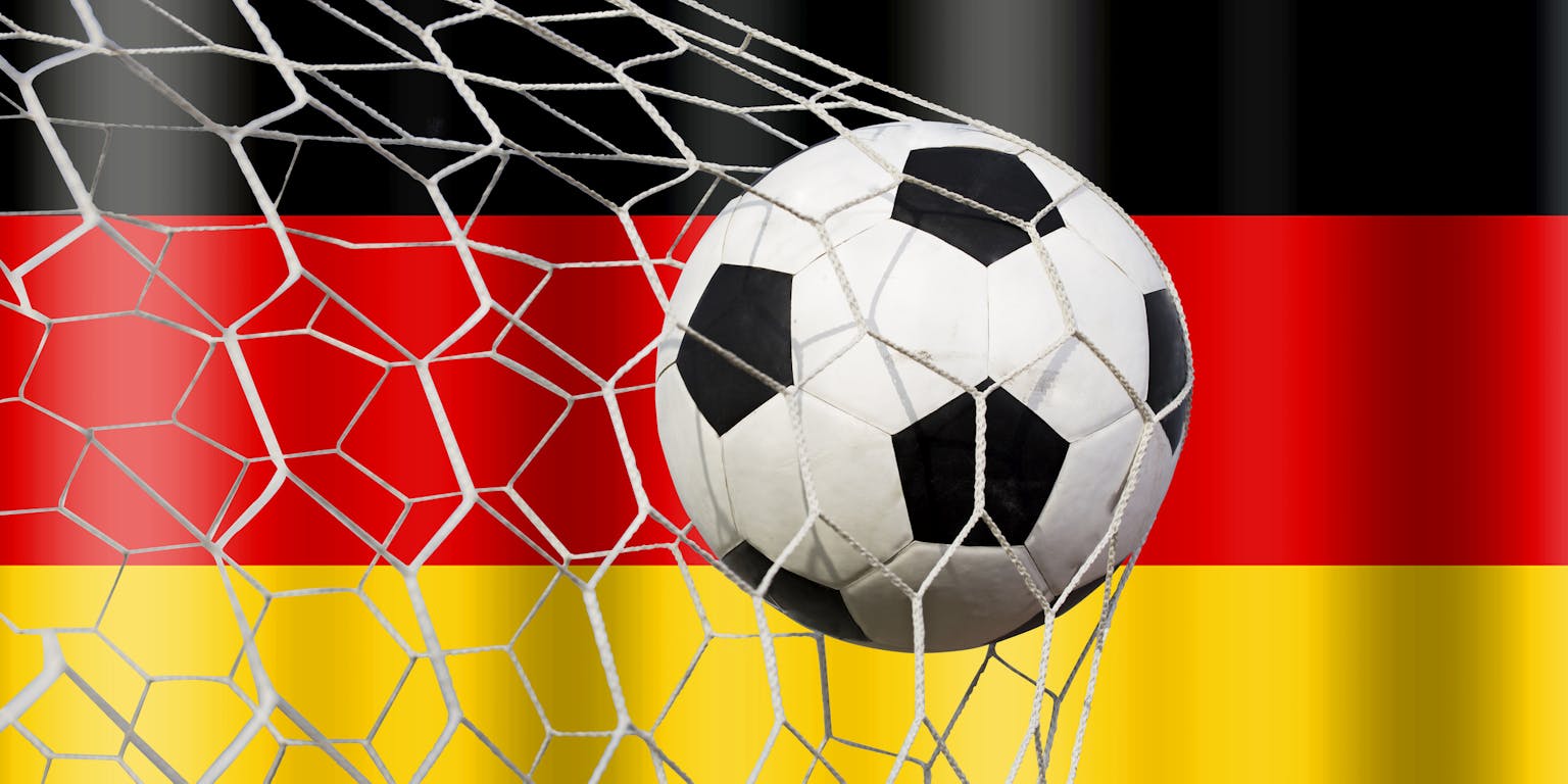 Voetbal in het net van de goal met op de achtergrond de Duitse vlag.