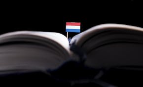 Een opengeslagen boek waar een Nederlands vlaggetje uitsteekt.