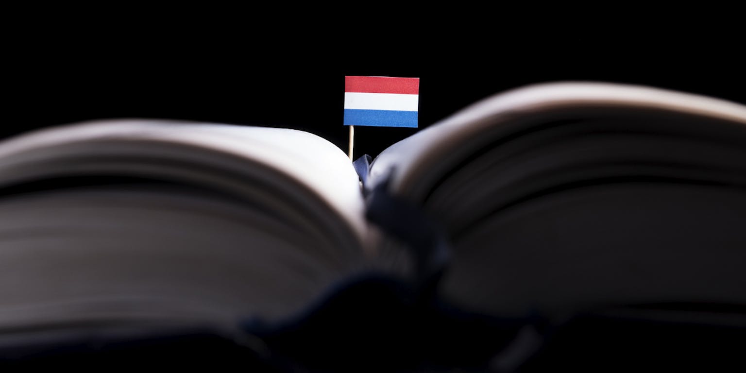 Een opengeslagen boek waar een Nederlands vlaggetje uitsteekt.