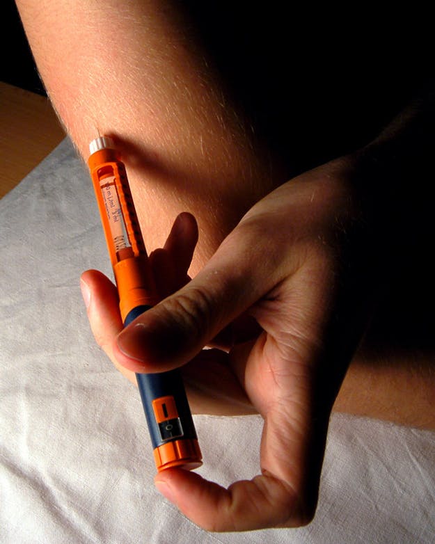 Een persoon die insuline in zijn arm spuit.