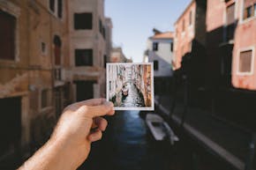 Een man die een foto van een kanaal in Venetië vasthoudt.