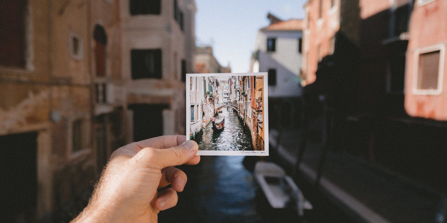 Een man die een foto van een kanaal in Venetië vasthoudt.