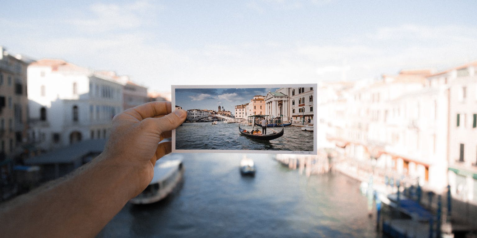 Een man die een foto van een boot in Venetië vasthoudt.