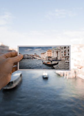 Een man die een foto van een boot in Venetië vasthoudt.