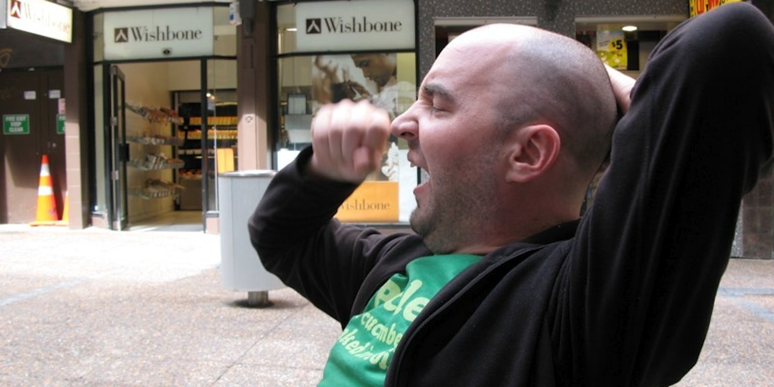 Een man zit op een bankje en gaapt.