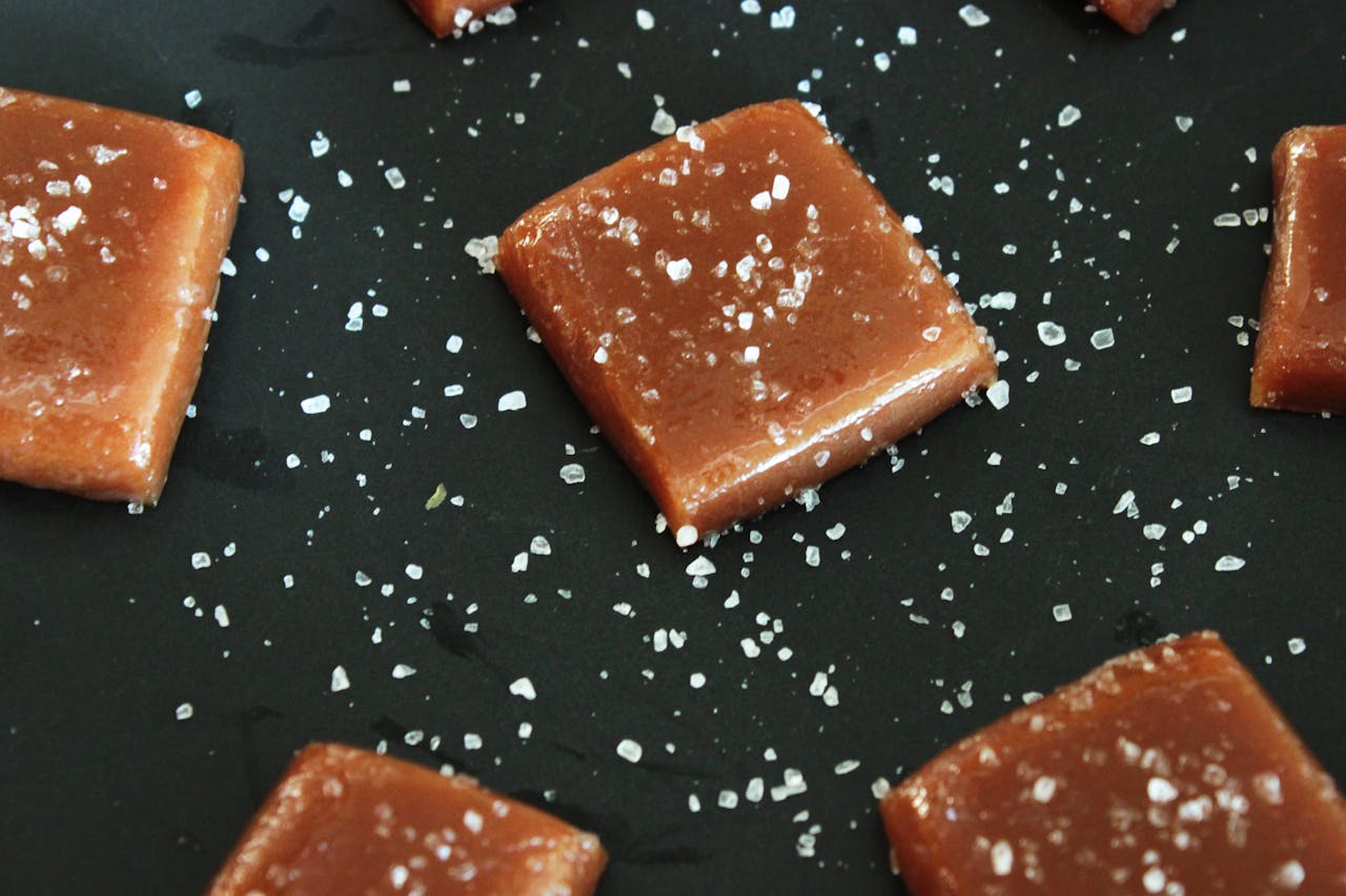 Karamel chocolade waar zout overheen wordt gestrooid op een zwarte plaat.