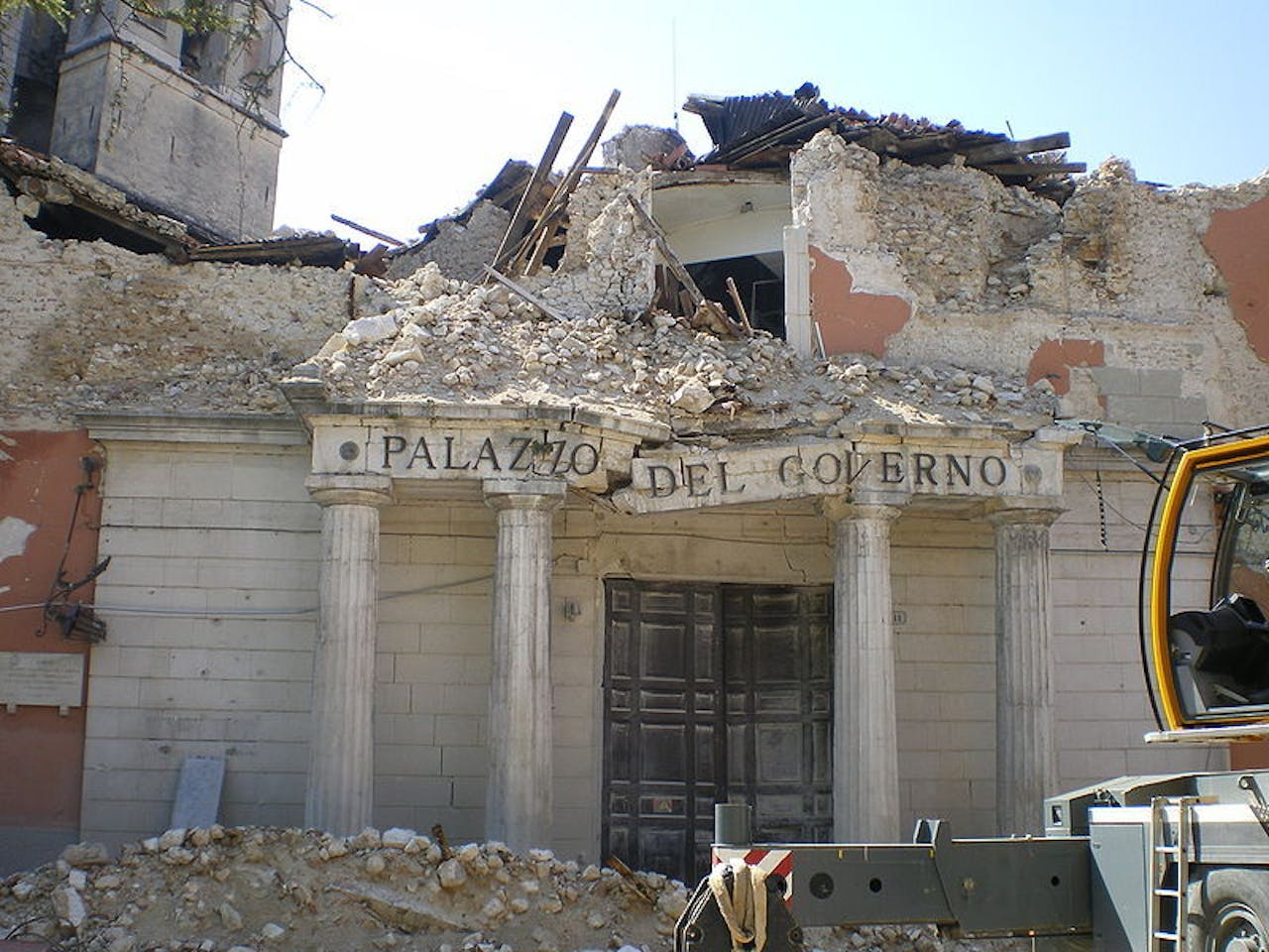 Een bulldozer staat voor ingestort Kloostergebouw Palazzo del Governo.