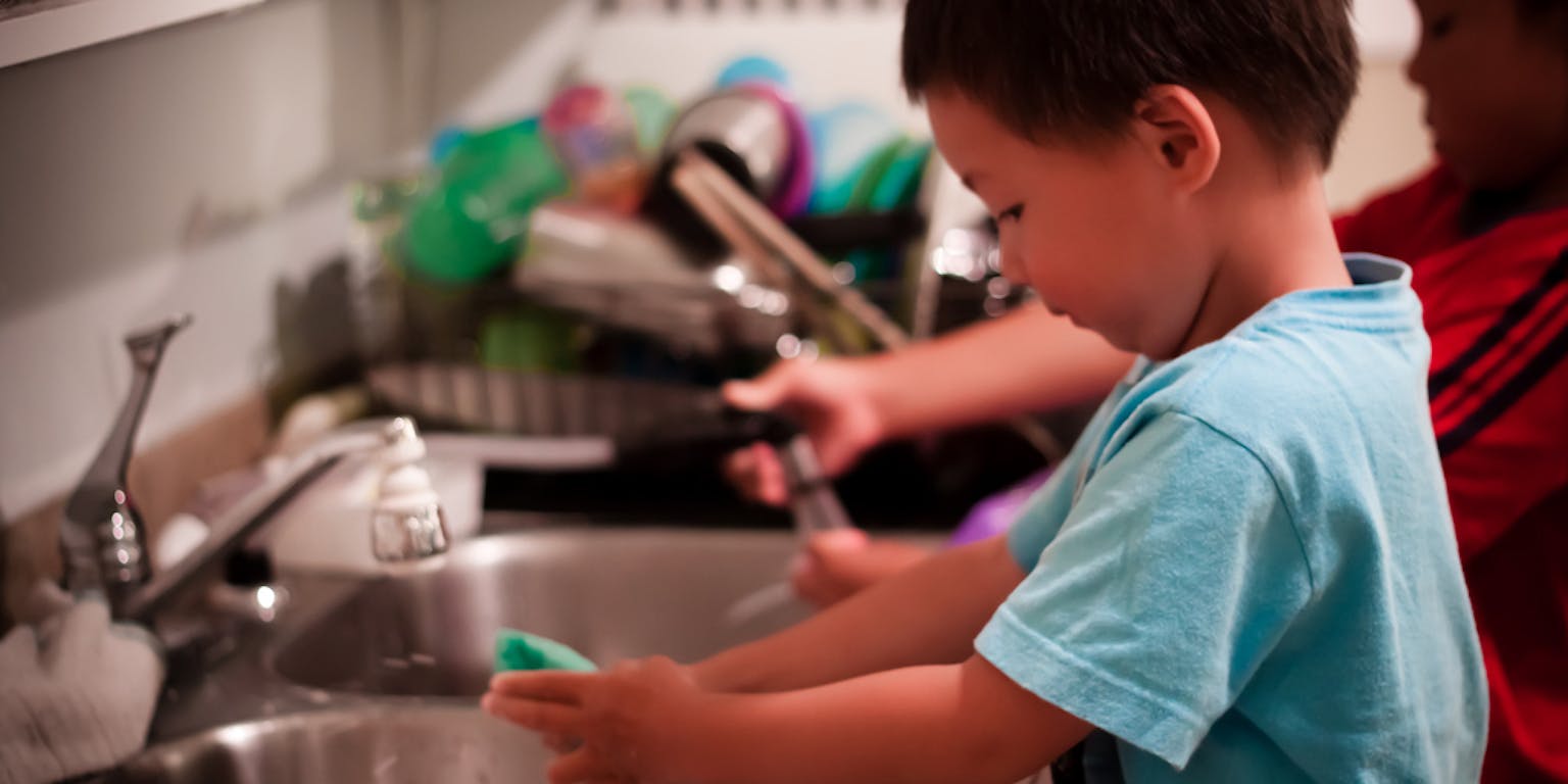 Een jongen wast zijn handen in een gootsteen.