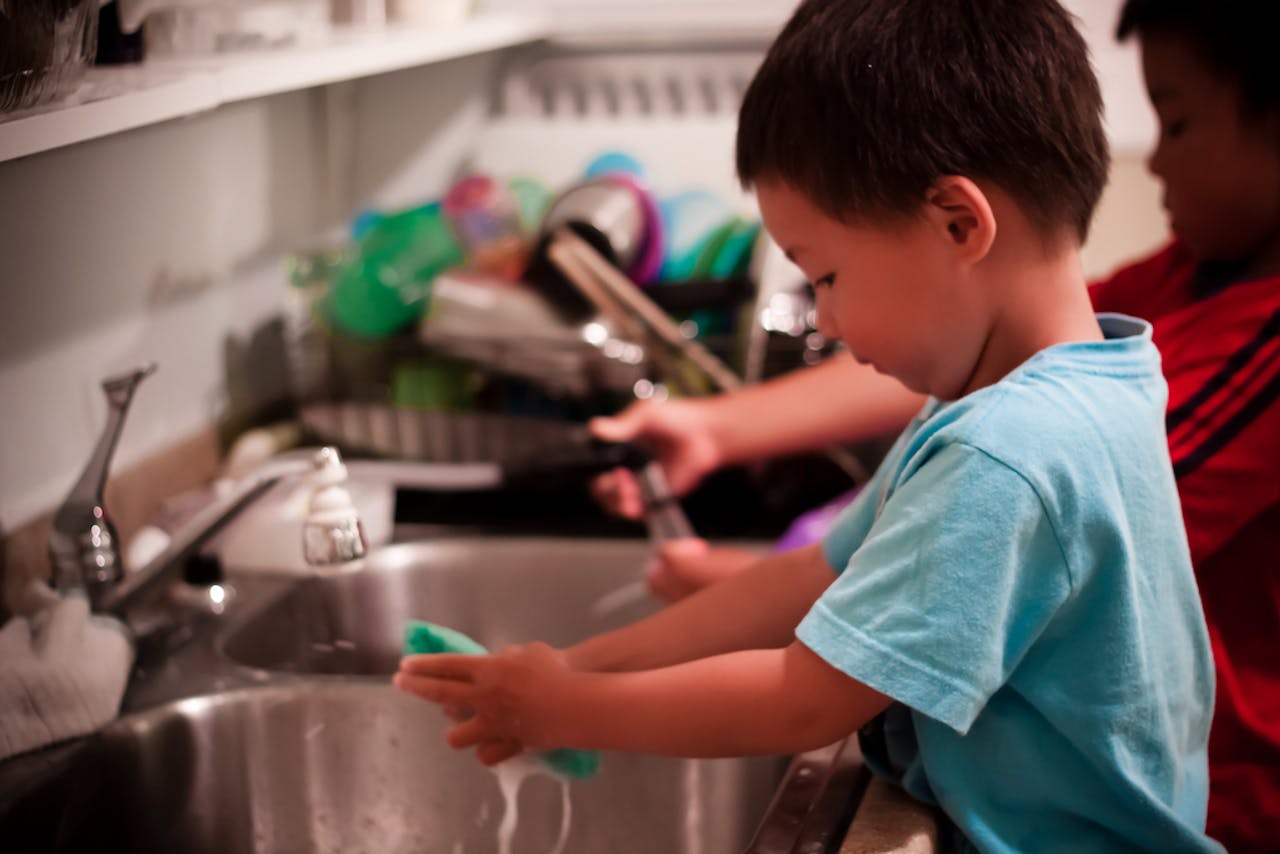 Een jongen wast zijn handen in een gootsteen.