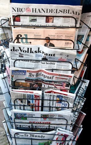 Een krantenrek met veel kranten erop.