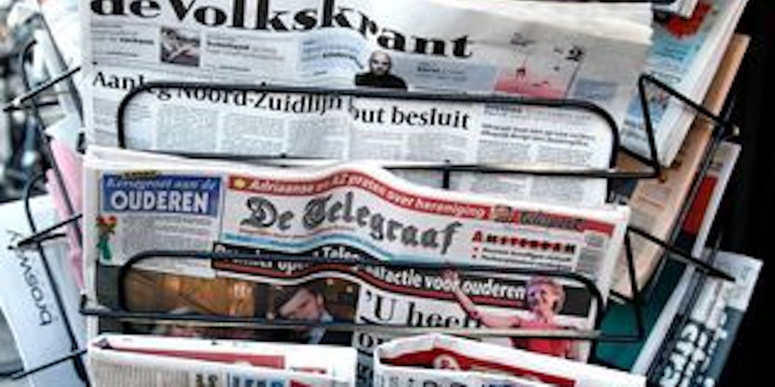 Een krantenrek met veel kranten erop.