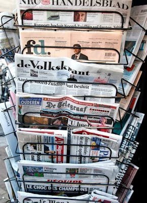 Een krantenrek met veel kranten erop.