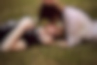 Een man en een vrouw liggen zoenend in het gras.