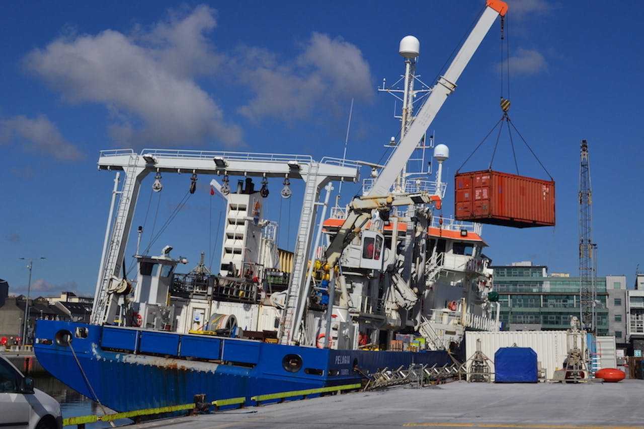 Een rode container wordt aan boord gehesen van onderzoeksschip Pelagia.