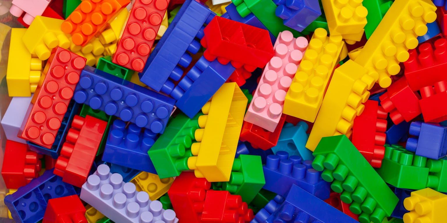 Berg van plastic bouwblokken in verschillende kleuren.