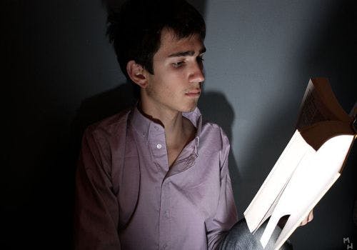 Een persoon die een boek leest in het donker.