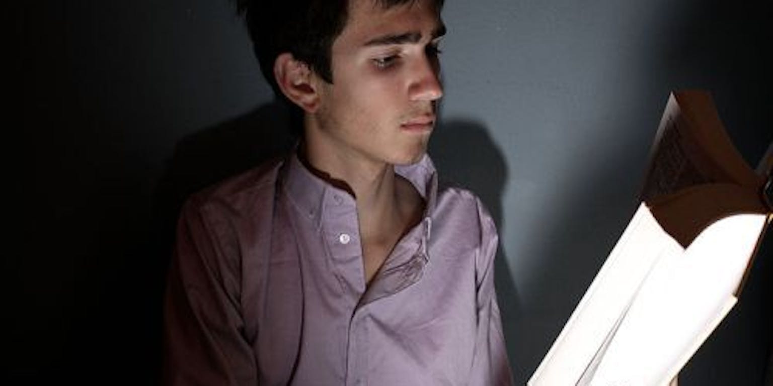 Een persoon die een boek leest in het donker.